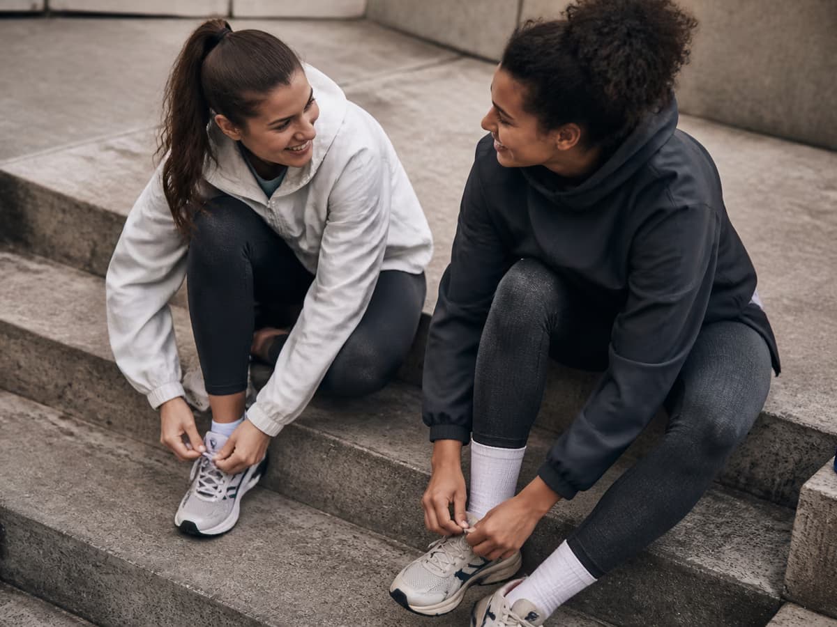 Two friends tie their running shoes together before a morning run.